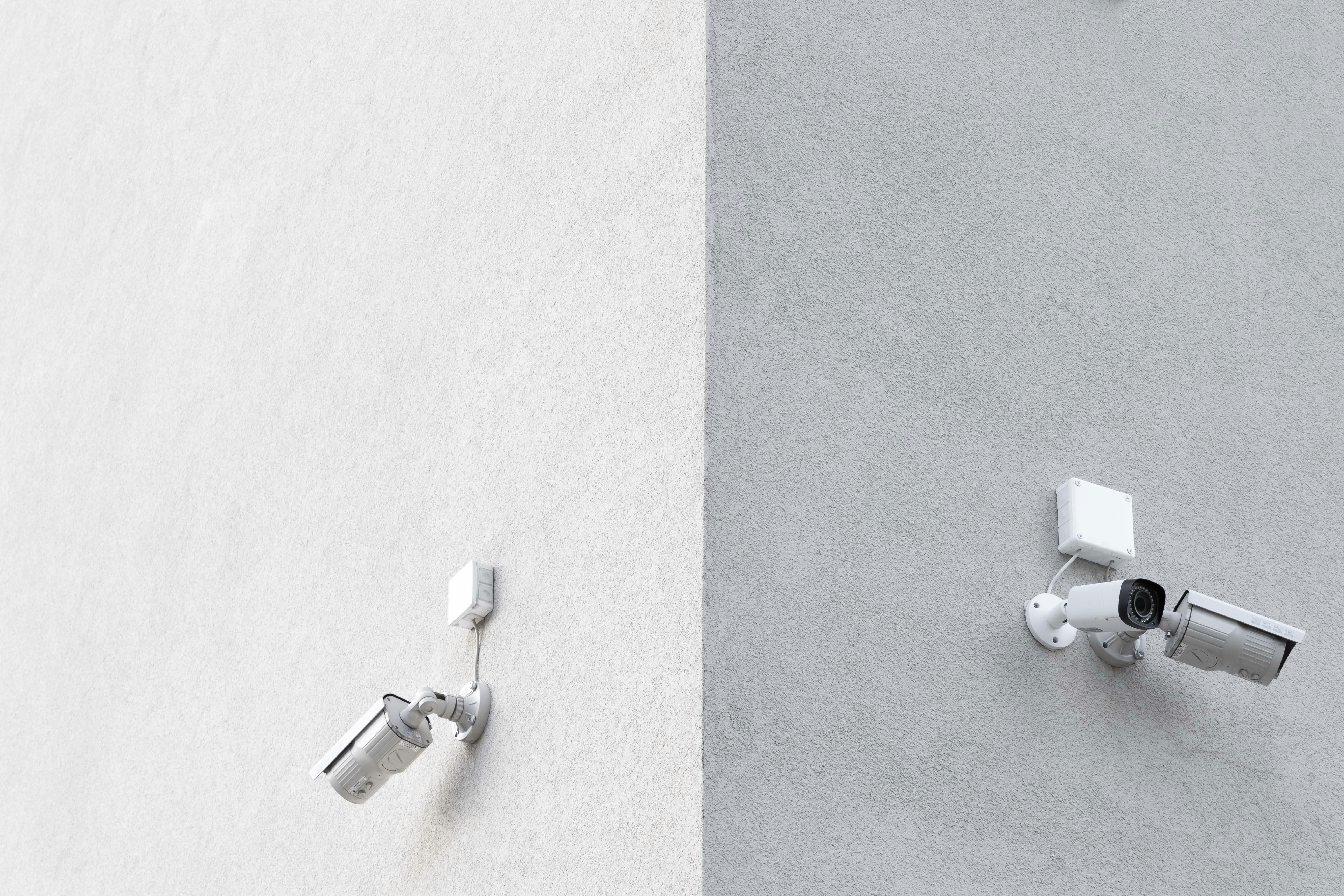 three white CCTV cameras mounted on wall